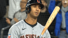 a baseball player wearing a cleveland uniform holds a bat