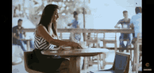 a woman sits at a table in a restaurant with a watermark that says ' zee ' on it