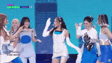 a group of young women are dancing on a stage with a sign that says the show