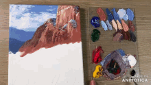 a painting of a mountain is being painted on a canvas next to a palette