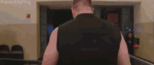 a man in a black tank top is walking down a hallway with the next big thing written on the bottom