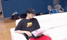 a man is sitting on a couch wearing a caution shirt .