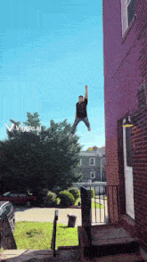a man is jumping in the air in front of a brick building with the words viggle.ai written below him