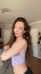 a woman in a purple crop top is dancing in a room