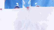 two girls are holding a white cloth in front of a blue background .