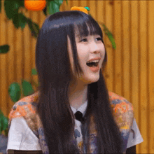 a girl with long black hair is smiling with her mouth wide open