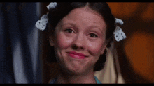 a young girl with a bow in her hair makes a funny face
