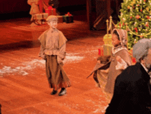 a group of people standing on a stage with a christmas tree in the background
