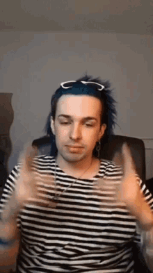 a man with blue hair wearing a striped shirt and sunglasses