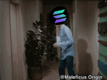 a man in a blue shirt is dancing in a hallway with a maleficus origin logo on his head