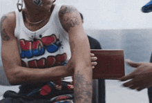 a woman with a tattoo on her arm is sitting on a chair with her arms crossed .