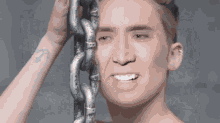 a man with a tattoo on his arm is smiling while holding a chain