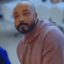 a man with a beard wearing a pink hoodie
