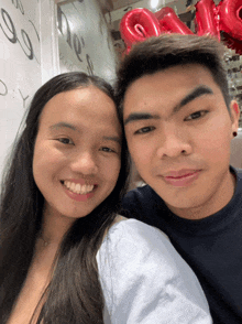 a man and a woman are posing for a picture with red balloons that say i love you on them