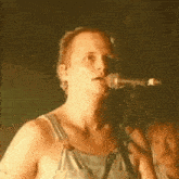 a man in overalls is singing into a microphone while playing a guitar .