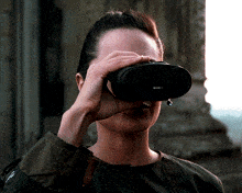 a woman looks through binoculars with a 10x30 objective lens