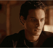 a close up of a young man 's face in a dark room looking at something .