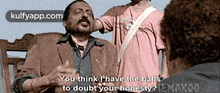 a man with a mustache is talking to another man while another man looks on .