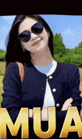 a woman wearing sunglasses and a black jacket is standing in front of the word mua