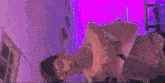 a man is laying on his back in a room with a purple light behind him .