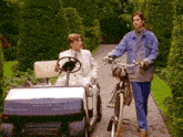 a man is driving a golf cart next to a woman riding a bike