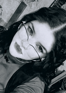 a black and white photo of a girl wearing glasses and a black shirt