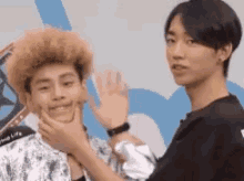 two young men are standing next to each other and one of them is holding another man 's neck .