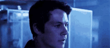 a close up of a man 's face in a dark room with blue lights .
