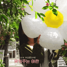 a woman in a green sweater is holding a balloon in front of her face