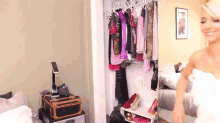 a woman in a white towel is standing in front of a closet full of clothes and shoes