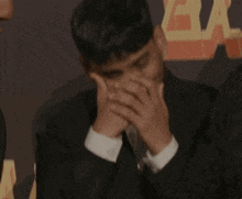 a man covering his mouth with his hands in front of a sign that says " the bay "