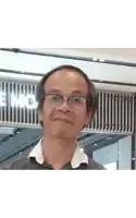 a man wearing glasses and a plaid shirt is standing in front of a building .