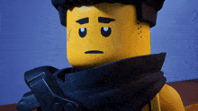 a yellow lego figure with a black scarf around his neck has a sad look on his face