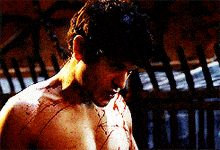a man without a shirt has blood on his chest