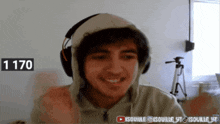 a young man wearing headphones and a hoodie has the number 1170 on his face