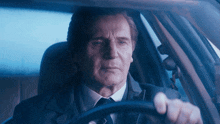 a man in a suit and tie is sitting in a car
