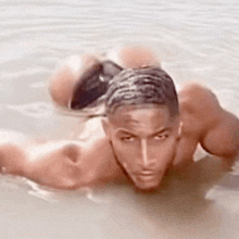 a shirtless man is laying in the water .