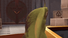 a green frog is sitting on a table in a room with a clock in the background .