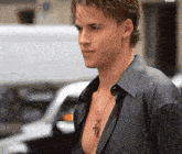 a young man wearing a black shirt and a necklace with a cross on it is walking down the street .