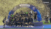 a group of soccer players are standing under a banner that says " winners "