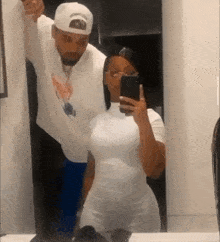 a man and a woman are taking a picture of themselves in a bathroom mirror .