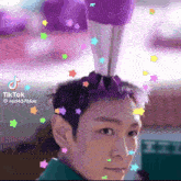 a man with purple hair has a purple object on his head