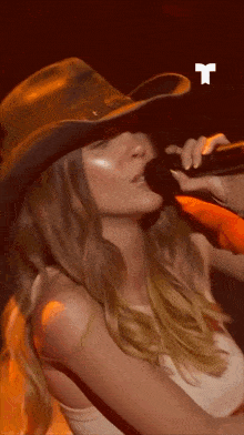 a woman wearing a cowboy hat with a white t on the bottom
