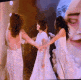 a group of women in white dresses are holding hands