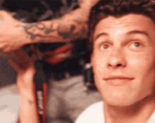 a close up of a man 's face with a tattoo on his arm looking up .