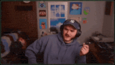 a man wearing headphones and a ny hat is standing in a room .