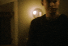 a blurry picture of a man in a dark room with a light behind him