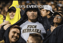 a man wearing a shirt that says fuck nebraska is surrounded by other people