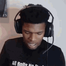 a man wearing headphones and a microphone is smiling and looking down .