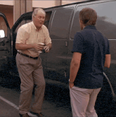 two men are standing in front of a van and talking